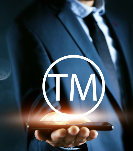 Hand reaching out to touch the word trademark surrounded by gears and cogs.